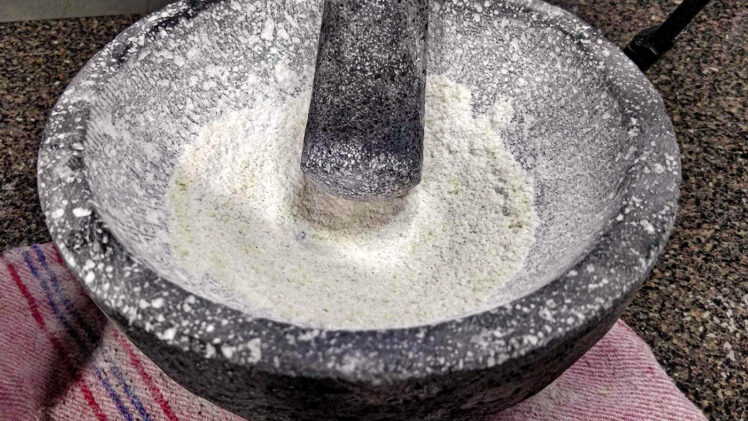 Förberedelse av molcajete med okokt ris för att ta bort stendamm
