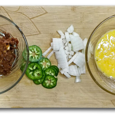 Förbered ingredienserna. Hacka löken, häll äggen i en skål och slå dem med en gaffel, skiva eller hacka chili om så önskas