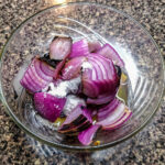 Lägg löken i en skål och häll på juicen samt salt