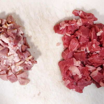 Skär kött och bacon i bitar