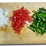 Hackade ingredienser, tomat, poblano, lök och vitlök
