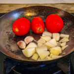 Lägg tomat, lök och vitlök i en het torr stekpanna utan olja