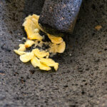 Krossa vitlöken försiktigt. Du vill inte slå för mycket mot molcajeten utan använda en krossande och sedan 