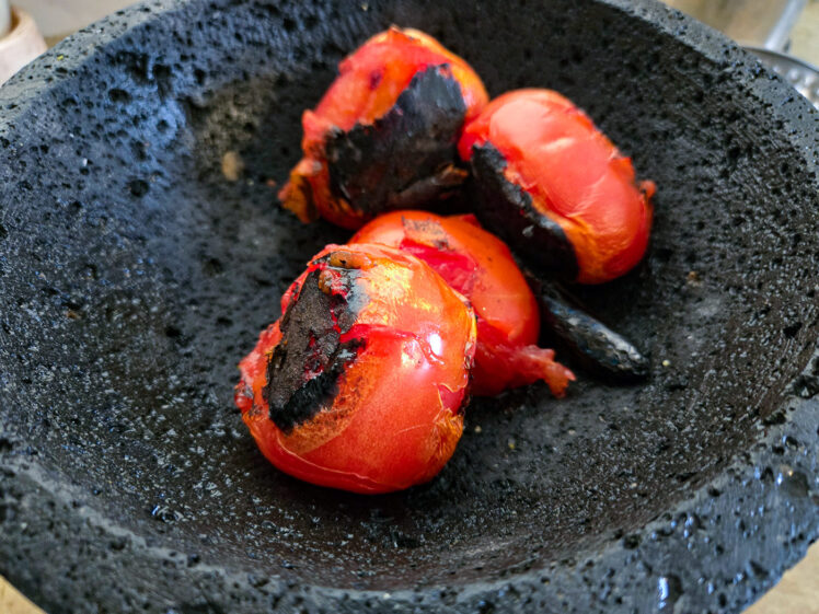 Lägg tomaterna och en av de rostade chilifrukterna i en blender eller molcajete