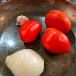 Rosta tomater, lök och vitlök (i sitt skal) i en torr het stekpanna