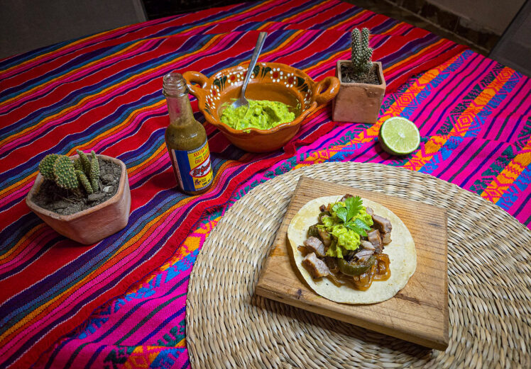 Servera kött, lök i tortilla med guacamole.